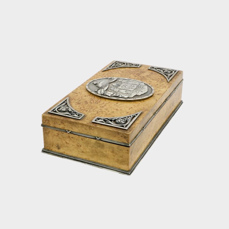 side view of Faberge cigar box by Anders Nevalainen with silver coat of arms in center and four silver corner floral scrolls