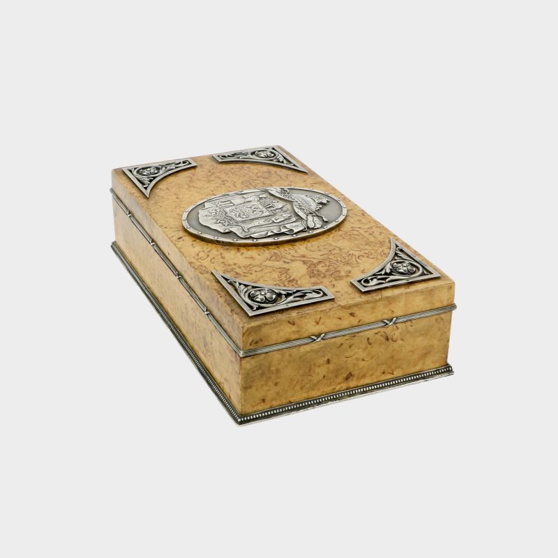 side view of Faberge cigar box by Anders Nevalainen with silver coat of arms in center and four silver corner floral scrolls