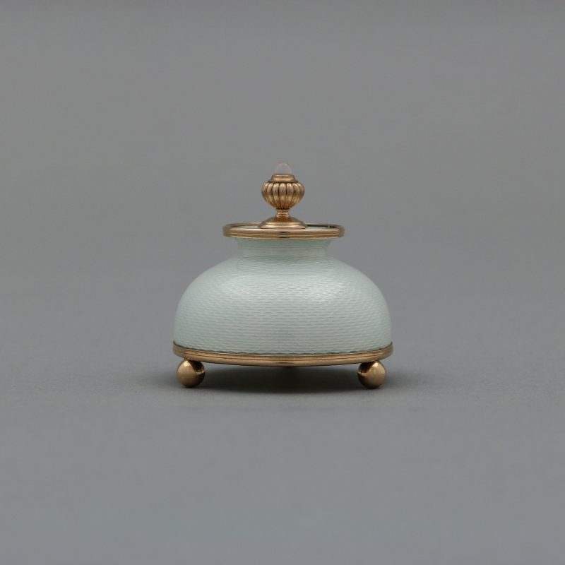 side view of Faberge enamel gum pot by Henrik Wigstrom, dome shaped body enameled in white with round gold mounts and finial