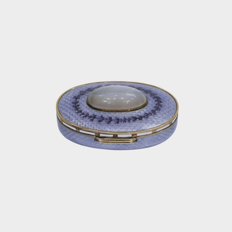 rear side view of Faberge pill box, of oval form, lilac guilloche enamel with cabochon moonstone centering hinged lid