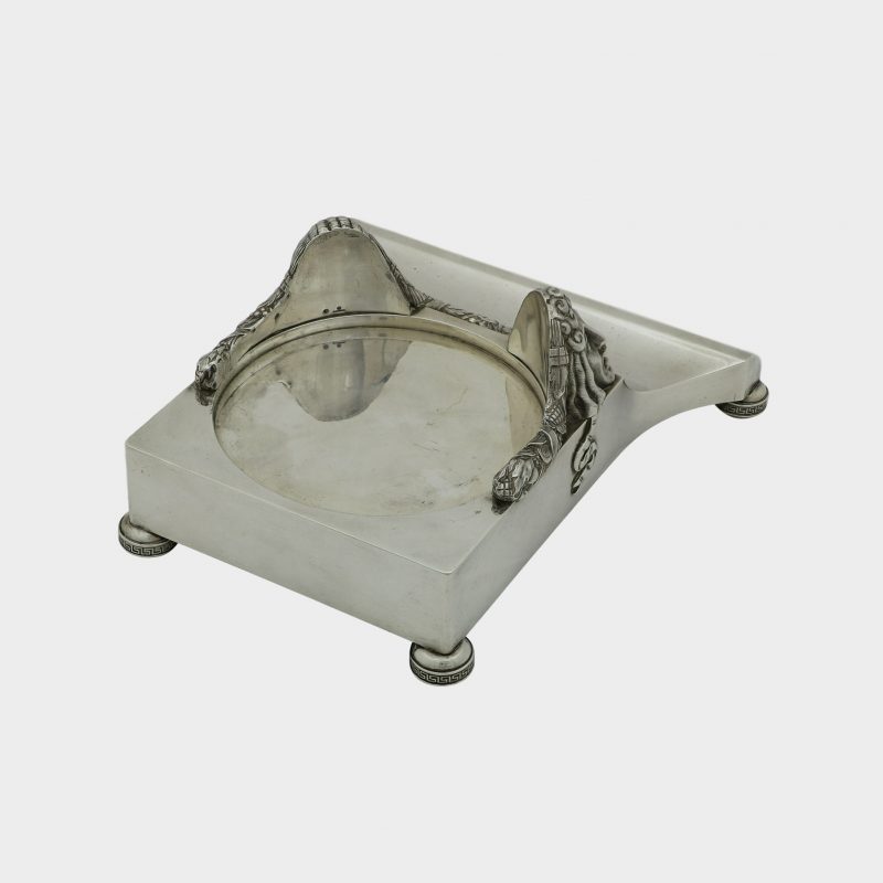 rear side view on Faberge inkwell trapezoid form silver stand without inkwell, front corners cast with theatrical masks