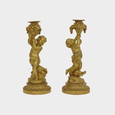 pair of antique gilt-bronze candlesticks, one cast as putti holding cornucopia, the other one holding basket with fruit