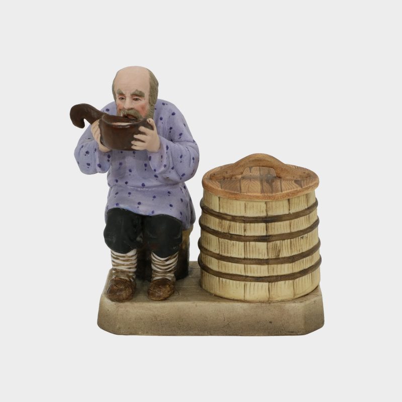 Russian porcelain figurine modeled as peasant seated beside a barrel, drinking water from a kovsh