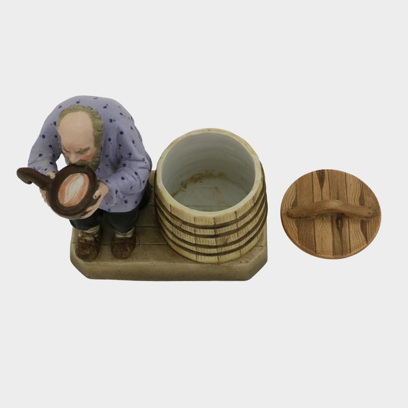 Russian figurine modeled as peasant seated beside a barrel, drinking water from a kovsh