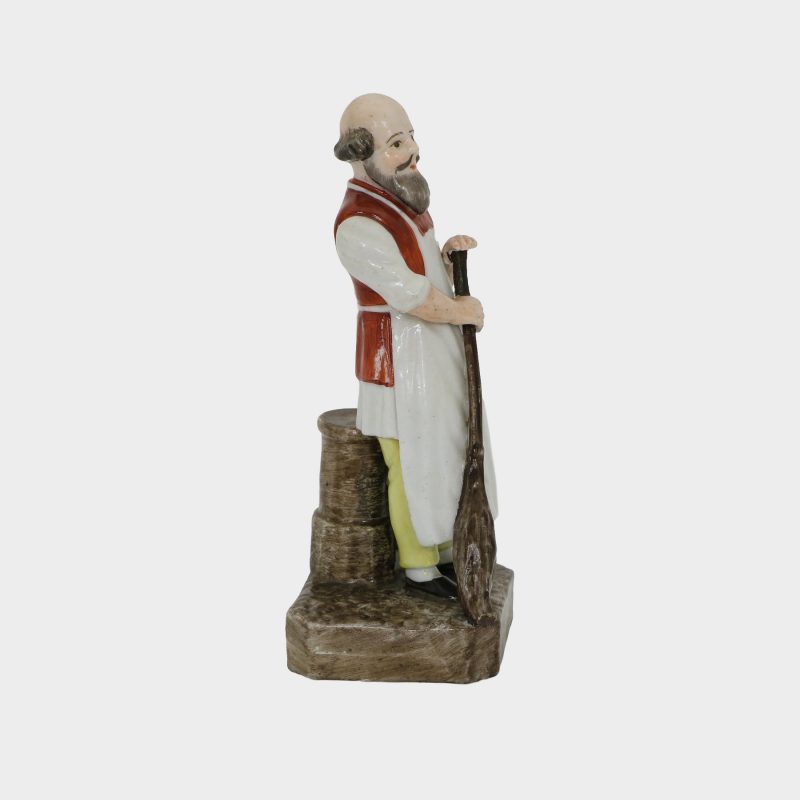 porcelain figurine modeled as yard keeper, holding a broom