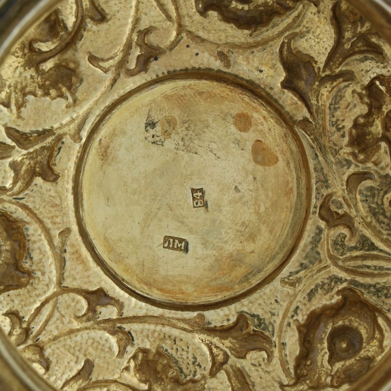 close-up of hallmarks on gilded lid of silver mug with lid decorated with scrolling foliage on stippled grounds