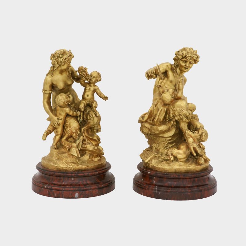 side view on pair of Clodion bronze sculptures on round marble bases cast as satyr and satyress with baby satyrs and putti