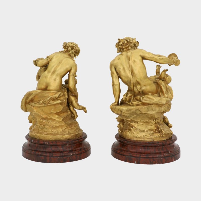 back view on pair of Clodion bronze sculptures on round marble bases cast as satyr and satyress with baby satyrs and putti