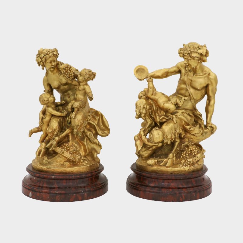 front view on pair of sculptures on round marble bases cast as satyr and satyress with baby satyrs and putti