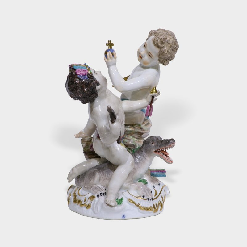Meissen porcelain figurine modeled as two frolicking putti one holding bow and arrow and other holding orb and scepter
