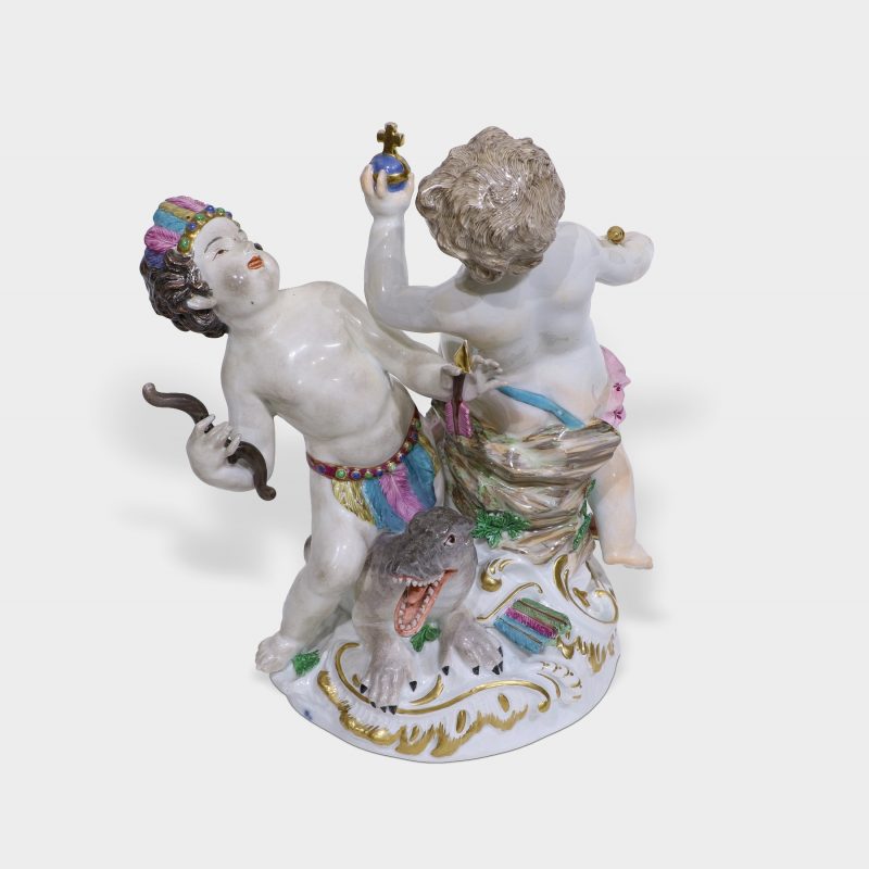 top view on porcelain figurine modeled as two frolicking putti one holding bow and arrow kneeling on mythical creature