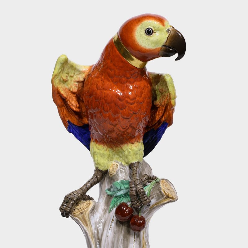 Close-up of Meissen porcelain parrot naturalistically modeled with brightly colored plumage perched on tree stump